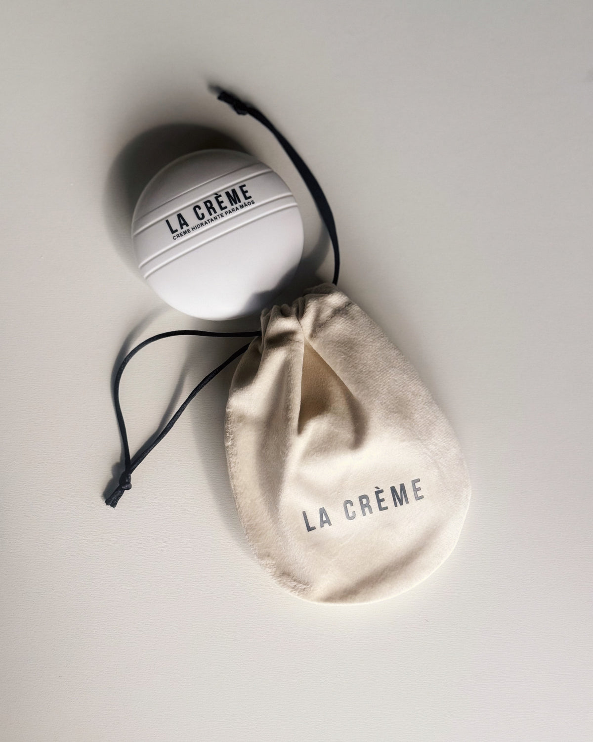 Pote do La Crème ao lado do saquinho de tecido da marca